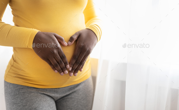 Pregnant woman holding palms in heart shape on her belly