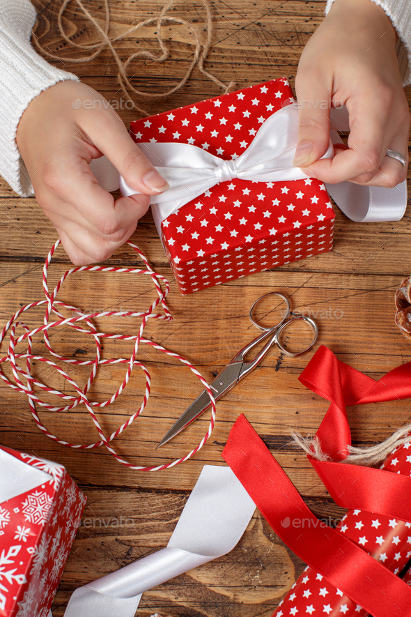 Woman ties a ribbon bow on a wrapped present