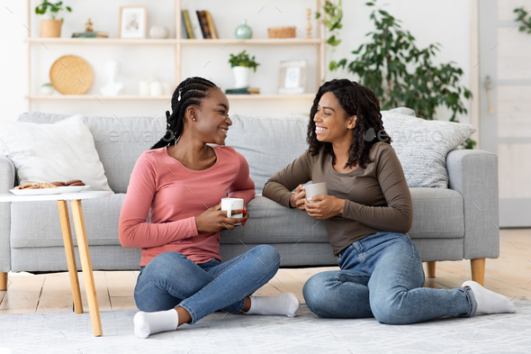 Smiling african american besties having conversation while drinking ...