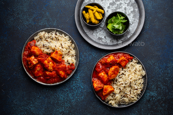 Chicken tikka masala dish with rice, flat Indian bread and spices in rustic metal plates - Stock Photo - Images