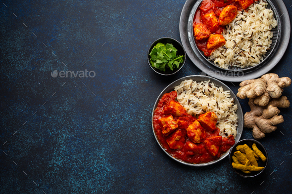 Chicken tikka masala dish with rice, flat Indian bread and spices in rustic metal plates - Stock Photo - Images