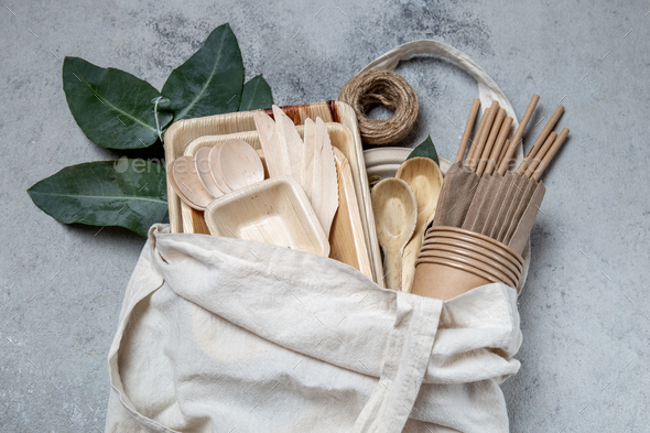 Eco craft paper and wooden tableware. Paper cups, dishes, bag, plates and wooden cutlery in linen - Stock Photo - Images