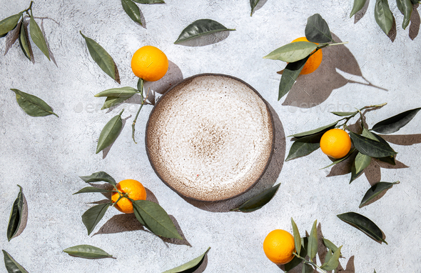 Whole oranges witl orange tree leaves on white background around empty plate. top view, flat lay - Stock Photo - Images