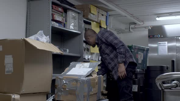 UK Indian Male Wearing Check Shirt Searching Different Shelves And Boxes In Office Basement. Locked alt