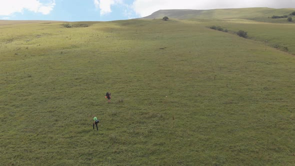 Aerial Shot of a Group of Tourists with Backpacks Climb the Mountain alt