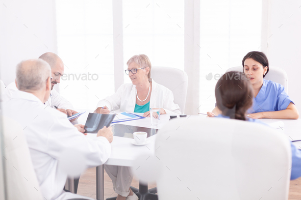 Academic meeting of expert doctors in hospital conference room. Clinic expert therapist talking with colleagues about disease, medicine professional