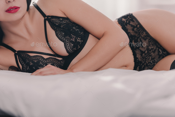 Beautiful sexy girl in black lace bra lying on bed - Stock Photo