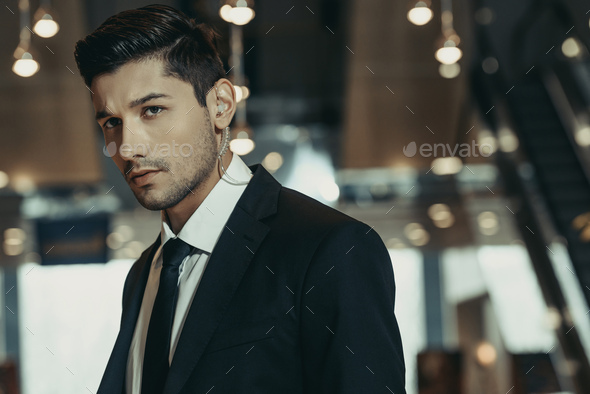 handsome security guard with security earpiece looking away - Stock Photo - Images