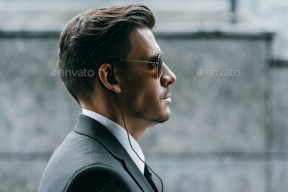 profile of handsome bodyguard with sunglasses and security earpiece - Stock Photo - Images