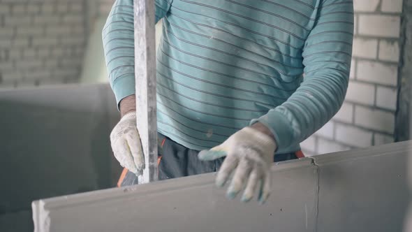 Man Holds Large Ruler and Measures Gypsum Plasterboard alt