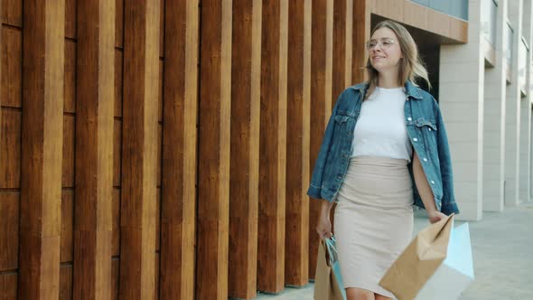 Slow Motion of Elegant Young Lady Walking Outdoors Carrying Shopping Bags Smiling alt