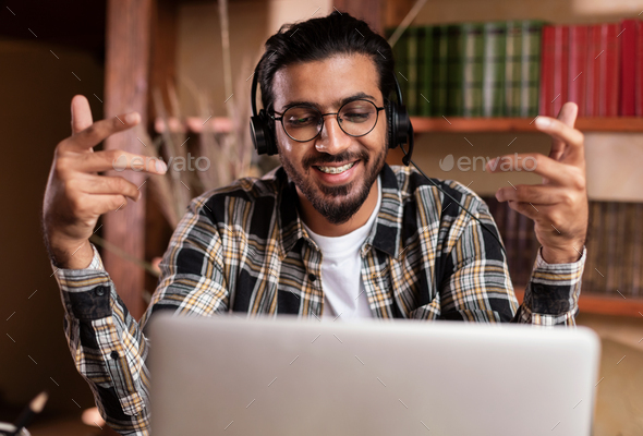 Indian guy having video call at laptop sitting at home
