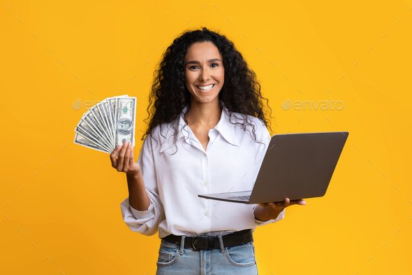 Online Lottery. Excited lady holding laptop and dollar cash, enjoying money prize