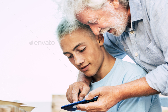 Portrait of young and old people grandfather and grandson together using a modern phone
