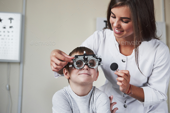 This is going fun. Doctor tuning the phoropter to to determine visual acuity of the little boy