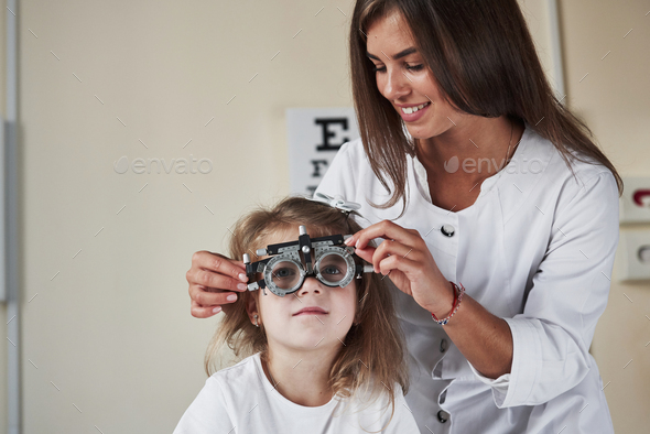 Tell when you can see that letter. Doctor checking little girl sight and tuning the phoropter
