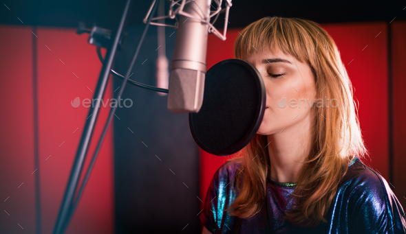 Young singer woman during music session at recording studio