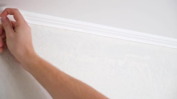 Man Cuts Wallpaper Near Ceiling Moldings Using Box Cutter and Putty Blade