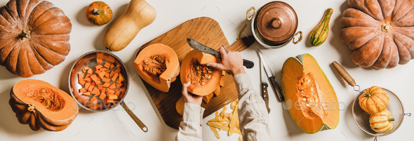 Female hands cutting pumpkin over white table, top view