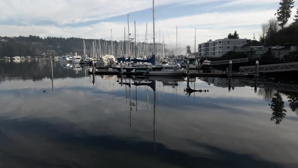 Glass-like water reflecting the sky and Fog shrouded Mount Rainier over Gig Harbor, aerial track up alt