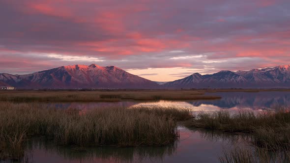 Colorful sunset over the marsh of Utah Lake reflecting the snow capped mountains alt