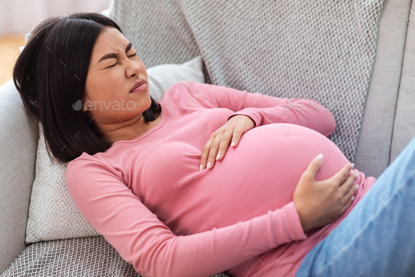 Pregnant Chinese Lady Suffering From Pain Touching Belly At Home