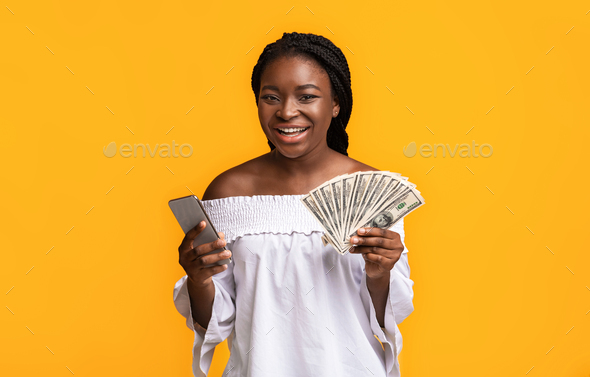 Online Credit. Happy African American Lady Posing With Smartphone And Dollar Cash