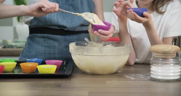Close Up of Childrens Hands Pouring Dough Into Cupcakes alt