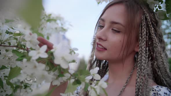 A Cute Girl with Dreadlocks Poses By a Tree with Leaves