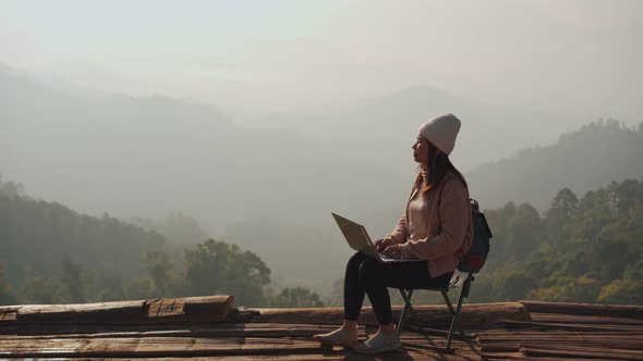 Young woman traveler working online using laptop and enjoying the beautiful nature landscape
