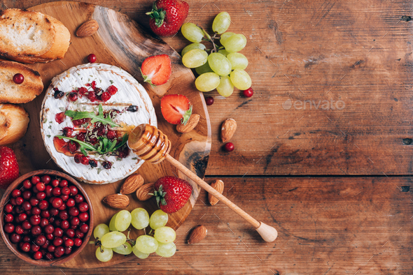 Baked camembert cheese with honey, rucola, cranberry, toasted bread, grape, strawberries