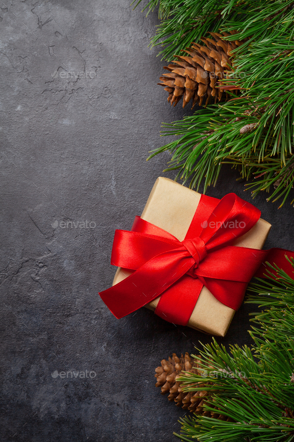 Christmas greeting card with fir tree and gift box on stone background and copy space for your xmas greetings. Top view flat lay
