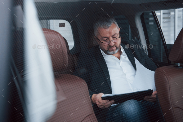 Need attention to details. Paperwork on the back seat of the car. Senior businessman with documents