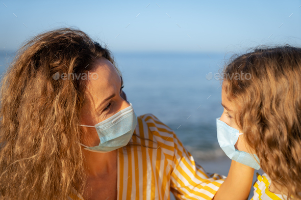 Happy mother and daughter wearing medical mask outdoor - Stock Photo - Images