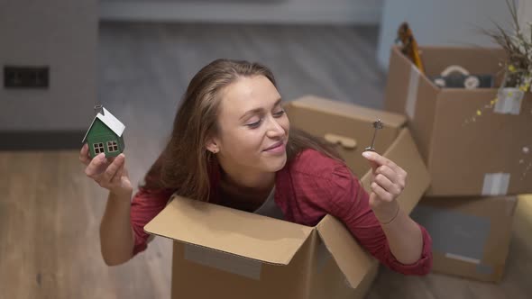 Cheerful Millennial Caucasian Woman with Toothy Smile Having Fun Sitting in Cardboard Box Showing alt