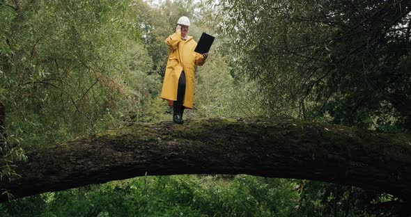 Ecologist Man in Helmet Stands on Fallen Tree He Talks on the Phone