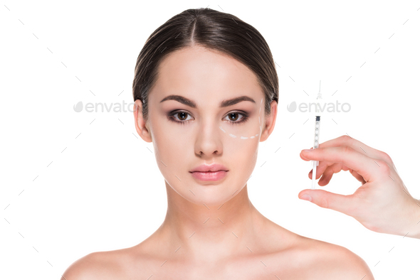 beautiful young woman with dotted line drawn on face for plastic surgery and hand holding syringe
