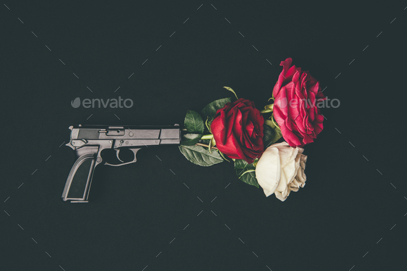 Top view of gun shooting with rose flowers isolated on black