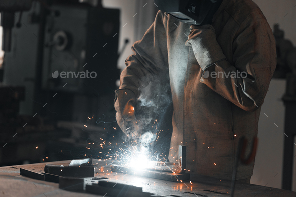 cropped shot of worker in protection mask welding metal at factory
