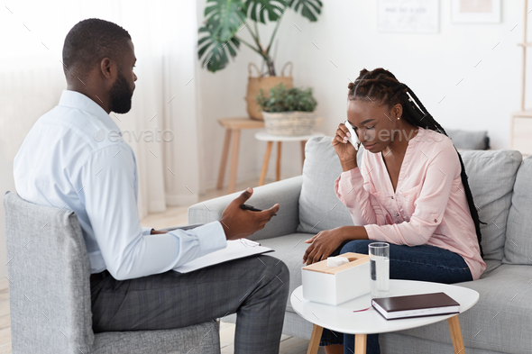 Black Psychologist Talking To Crying Woman During Therapy Session At His Office