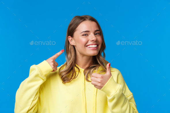 Cheerful and pleased, satisfied good-looking european female pointing at pierced ear and smiling