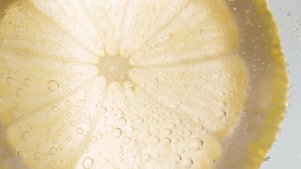 Slow Motion Macro Shot of a Lemon Slice in Water Bubbles Drinking Cold Lemonade alt