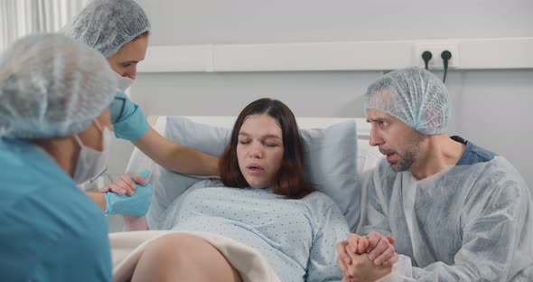 Husband and Nurses Supporting Pregnant Woman Hardly Breathing During Child Birth alt