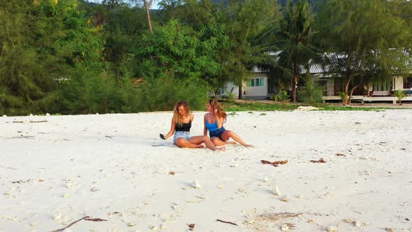 Beautiful women happy together on relaxing lagoon beach trip by aqua blue sea and white sand backgro alt