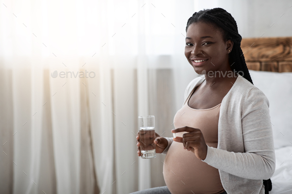 Prenatal Vitamins. Pregnant Black Woman Holding Supplement Pill And Glass Of Water