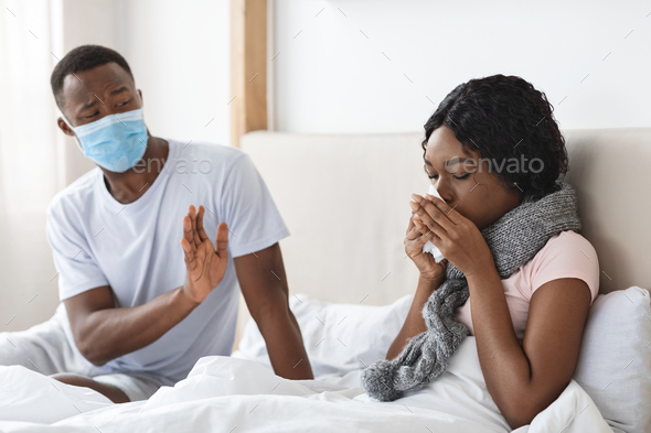 Black man wearing face mask while his wife is sick