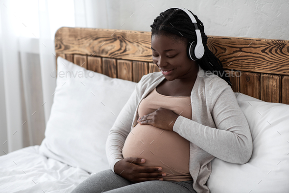 Pregnancy Music. Happy Black Pregnant Woman In Wireless Headphones Relaxing On Bed
