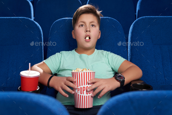 Shocked teen with opened mouth watching movie in cinema