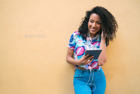 Young afro woman listening music on tablet.