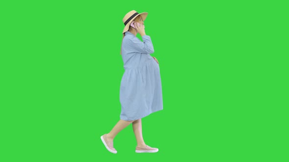 Beautiful Caucasian Pregnant Woman Making a Call on Summer Walk Outdoors on a Green Screen, Chroma alt